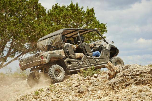 First Service: ATV (under 100cc) 4 An off-road vehicle with four passengers drives uphill on rocky terrain with trees in the background.